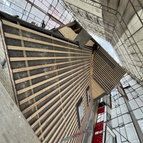 Tømrer udfører tømrerarbejde med tagrenovering og nyt tag på større ejendom