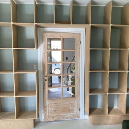 Tømrer udfører udskiftning af døre og montering af indbygget reol som del af tømrerarbejde i bolig