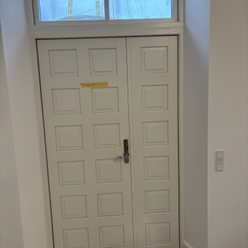 Tømrer udfører udskiftning af hoveddør med overparti som del af professionelt tømrerarbejde