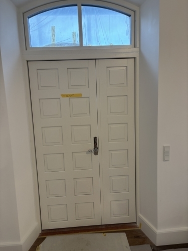 Tømrer udfører udskiftning af hoveddør med overparti som del af professionelt tømrerarbejde