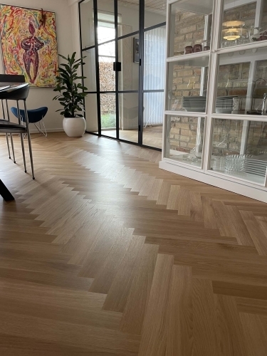 Snedkerarbejde med sildebensgulv i stue med glasvæg og murstensdetaljer