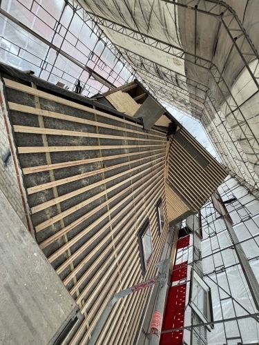 Tømrer udfører tømrerarbejde med tagrenovering og nyt tag på større ejendom